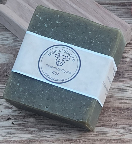 Green soap bar with a white label on a wooden block, placed on a wooden surface.