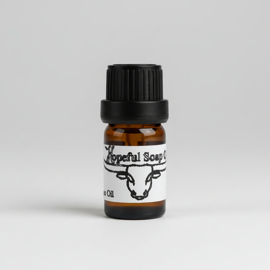 Hand holding a small brown bottle with a label on a wooden surface