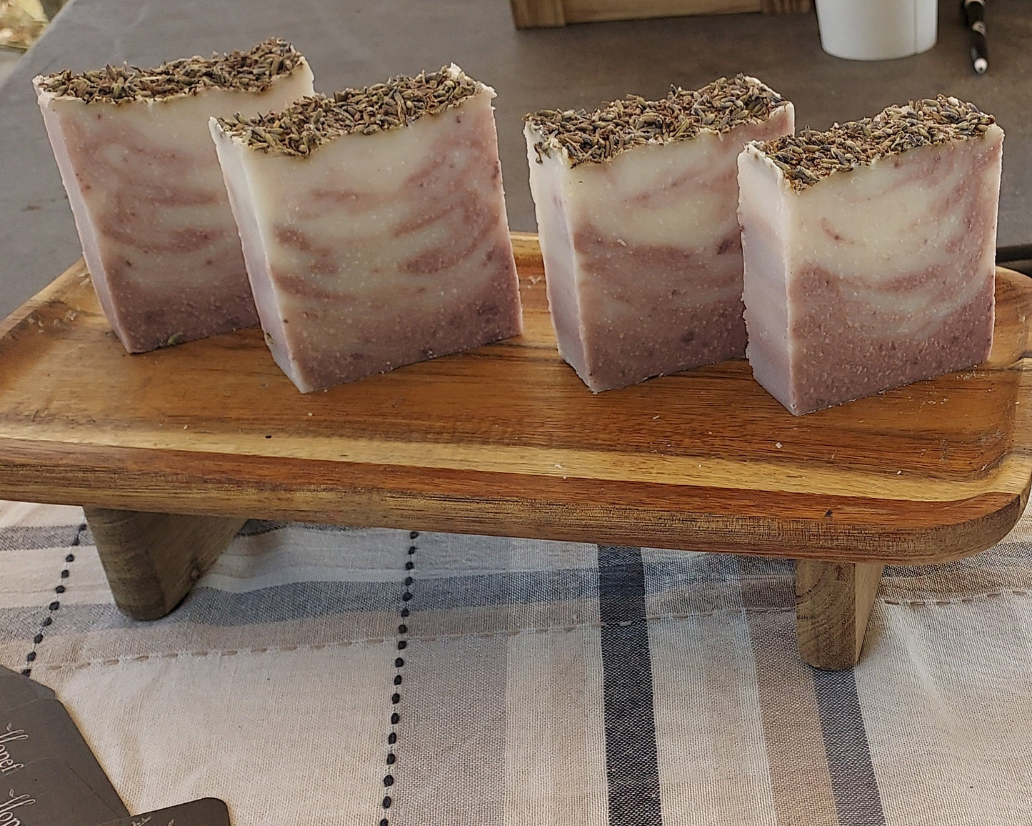 Three soaps on a wooden stand with a chalkboard sign in the background.