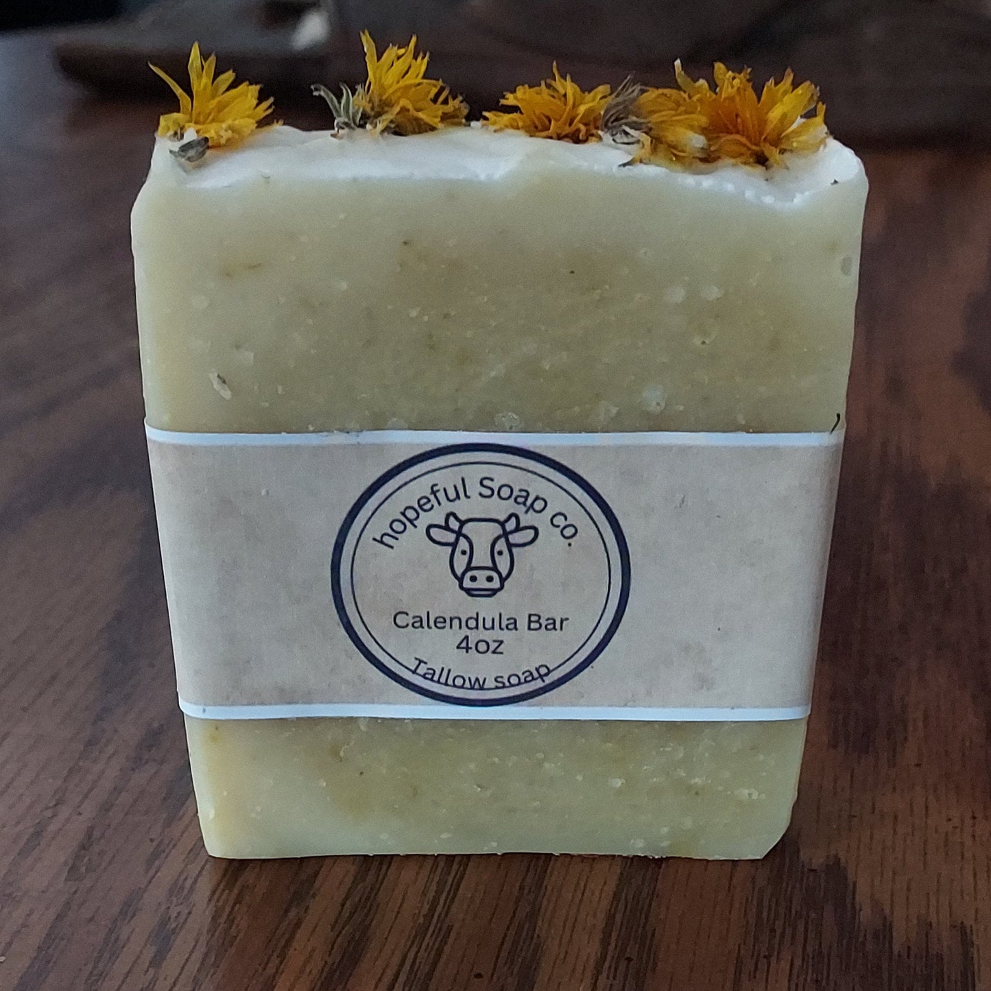 Bar of soap with a decorative band featuring a logo on a wooden surface