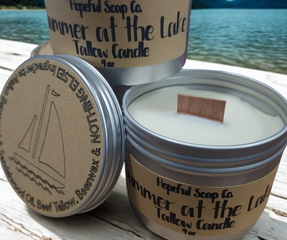 Tallow candle in a metal container with 'Hopeful Soap Co' branding, set against a lakeside background.